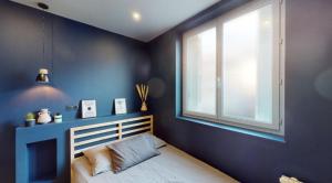 a bedroom with blue walls and a bed with a window at Jupiter Paris in Champigny-sur-Marne