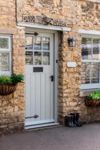 ein Backsteinhaus mit einer weißen Tür und zwei Fenstern in der Unterkunft Cottage Central Location Parking Fireplace Garden in Bourton on the Water
