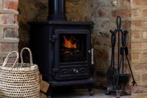 ein schwarzer Ofen mit einem Feuer darin neben einem Korb in der Unterkunft Cottage Central Location Parking Fireplace Garden in Bourton on the Water