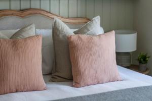 un letto con cuscini rosa e bianchi di Cottage Central Location Parking Fireplace Garden a Bourton on the Water