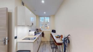 a kitchen with white cabinets and a counter top at Jupiter Paris in Champigny-sur-Marne