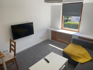 a living room with a couch and a tv at Glen Cannich - Top Location, 2BR Accessible apt in Inverkeithing
