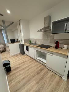 een keuken met witte kasten en een houten vloer bij Studio Cosy in Saint-Gaudens