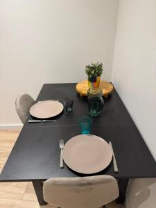 een zwarte tafel met twee witte platen erop bij Studio Cosy in Saint-Gaudens
