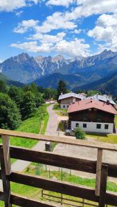 a fence with a view of a house and mountains at HG Hotel La Caminatha in Val di Zoldo