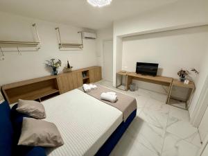a bedroom with two beds and a desk and a television at Albanèse Luxury Rooms in Porto Empedocle