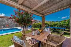 a patio with a table and chairs and a pool at Villa Rizolia Enea by Villa Plus in Lithakia