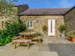 Una mesa de picnic y bancos frente a una cabaña. en 4 Bed in Bamburgh 83373, en Belford