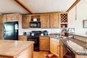 a kitchen with wooden cabinets and a black refrigerator at View House in Fraser