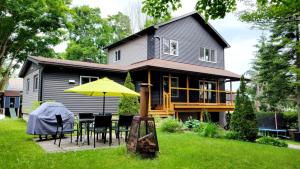une maison avec une table, des chaises et un parasol jaune dans l'établissement Chalet Ô Lac-Brome, 3ch, 8 personnes, à Lac-Brome