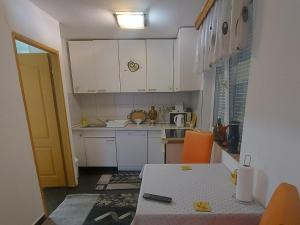 a small kitchen with white cabinets and a table at Apartmani GS ***** Zavidovici in Zavidovići