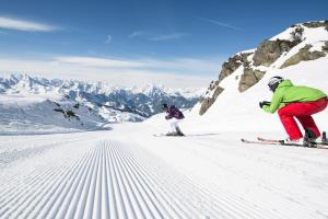 two people are skiing down a snow covered mountain at Hotel Maria Theresia in Gerlos +51 photos