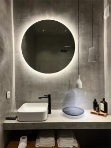 a bathroom with a sink and a round mirror at hellofrom Beach House in Loutrá Elevtherón +97 photos