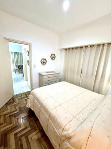 a white bedroom with a bed and a mirror at Alsina Mdq in Mar del Plata