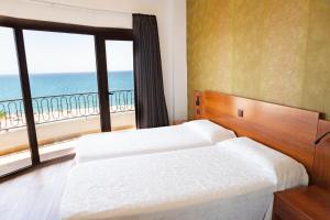 a bedroom with two beds and a view of the ocean at Hotel Haromar in Calella
