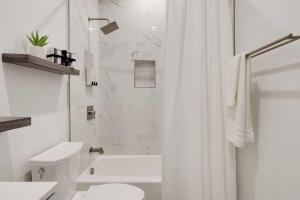 a white bathroom with a toilet and a shower at 1Bed 1Full Bath, Full Kitchen, Queen Sofa Bed, Queen Bed, Parking, EV in Northridge +12 photos