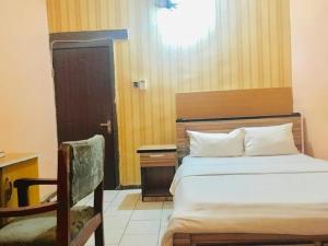 a bedroom with a bed and a desk and a chair at Abuja Bays Garden Hotel Ltd in Mama