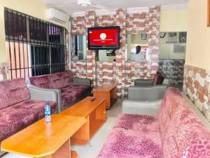 a living room with two couches and a tv at Abuja Bays Garden Hotel Ltd in Mama
