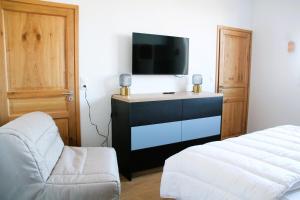 una camera con letto, TV e sedia di Les Pieds dans l'Eau a Roscoff