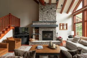 sala de estar con chimenea de piedra y mesa en Deluxe Ski in-out - HotTub - Fire - PingPong - View, en Mont-Tremblant