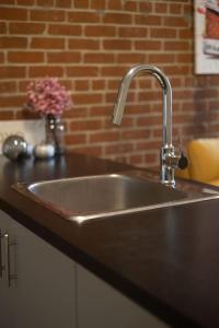 a stainless steel sink in a kitchen with a brick wall at Sleek 2BR in Heart of Downtown Montreal in Montréal