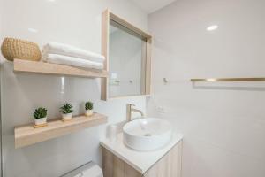 a white bathroom with a sink and a mirror at Modern Coastal Design 1 BR Condo Golf View BGC in Manila +16 photos