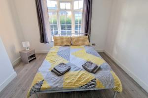 ミッチャムにある6-bedroom House in Morden, London (Zone 4)のベッドルーム1室(黄色と青の毛布付きのベッド1台付)