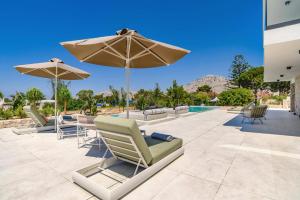a patio with chairs and an umbrella and a pool at Villa Pefkos Cove by Villa Plus in Pefki Rhodes