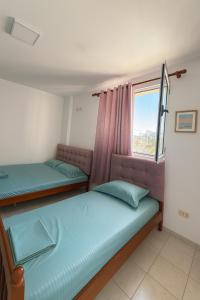 una camera da letto con due letti e una finestra di Hotel Ardjan a Golem
