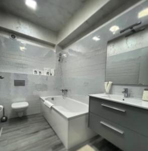 a bathroom with a tub and a toilet and a sink at White Tower Apart Hotel in Mamaia +23 photos