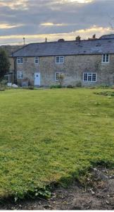 a large brick building with a grass field in front of it at Broadwindsor Cottage in Broadwindsor