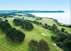 an overhead view of a golf course with trees and water at Sandy Nights in Tywardreath