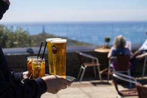 a person holding two glasses of beer on a table at Cape Cornwall Club in St. Just