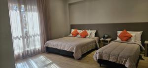 a bedroom with two beds with orange pillows at Gran Hotel Dakar in Mendoza