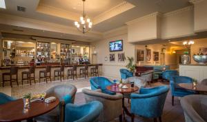 Kilkenny River Court Hotel في كيلكيني: مطعم بطاولات وكراسي وبار