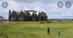a man swinging a golf club on a golf course with a house at Crowe's Bridge House in Quilty