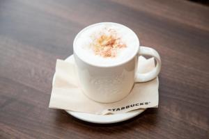 a cup of coffee sitting on a plate on a table at Knowsley Inn & Lounge in Knowsley +24 photos