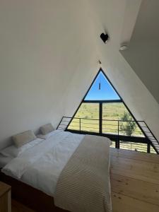 a bed in a room with a large window at TriPeak in Bjelašnica