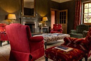 a living room with red chairs and a fireplace at B&B Kasteelhoeve de Kerckhem in Wijer