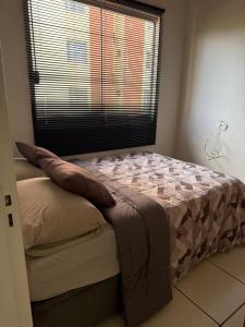 ein Bett in einem Schlafzimmer mit einem großen Fenster in der Unterkunft Apto funcional e bem equipado in Maringá