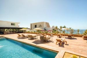 una piscina con mesas y sillas junto a un edificio en 3 priv apt gpo 16 px vista mar, en Nacionalista