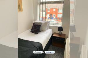 ein kleines Bett in einem Zimmer mit Fenster in der Unterkunft 3-Bedroom House in Warrington with Free Parking Ideal for Contractors and Family Stays in Warrington