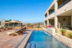 a pool at a hotel with tables and benches at For couples, petfriendly 2 BR ocean view 18 4pax in Cabo San Lucas