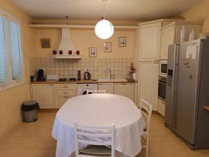 a kitchen with a white table with chairs and a refrigerator at Le cœur de saint Florent in Saint-Florent