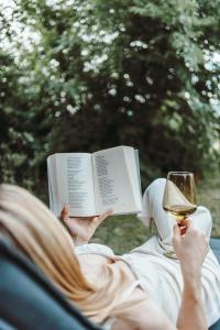 a woman reading a book and a glass of wine at História Présház boutique Nagyréde in Gyöngyös