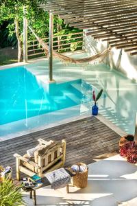 a swimming pool with a chair next to a wooden deck at Suítes na Vila Mansinha - perto do quadrado in Trancoso