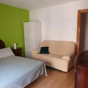 a bedroom with a bed and a couch in a room at Habitación en centro de Alicante in Alicante