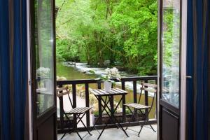 uma varanda com uma mesa e cadeiras e um rio em Le Moulin Des Ruats em Avallon