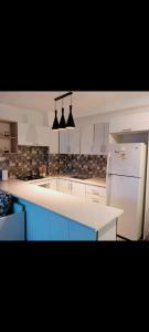 a kitchen with blue cabinets and a white refrigerator at L'appartement Bleu in Bejaïa