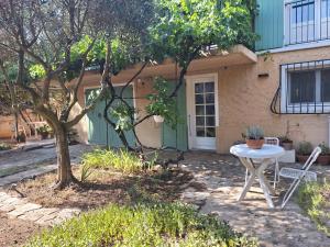 una mesa y una silla frente a una casa en Le jardinet d'Emma - Appart RDC avec jacuzzi, parking, au calme, en Raphèle